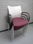A set of four moulded plastic and Burgundy fabric stacking office armchairs