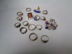 A box of a collection of silver and costume rings and a costume brooch