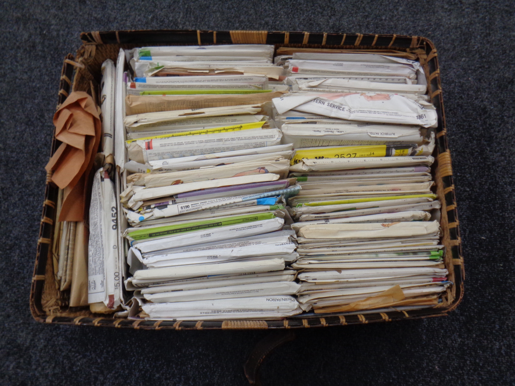 A wicker basket containing a quantity of vintage knitting patterns