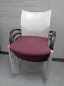 A set of four moulded plastic and Burgundy fabric stacking office armchairs