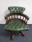 A captain's swivel desk chair upholstered in a dark green button leather