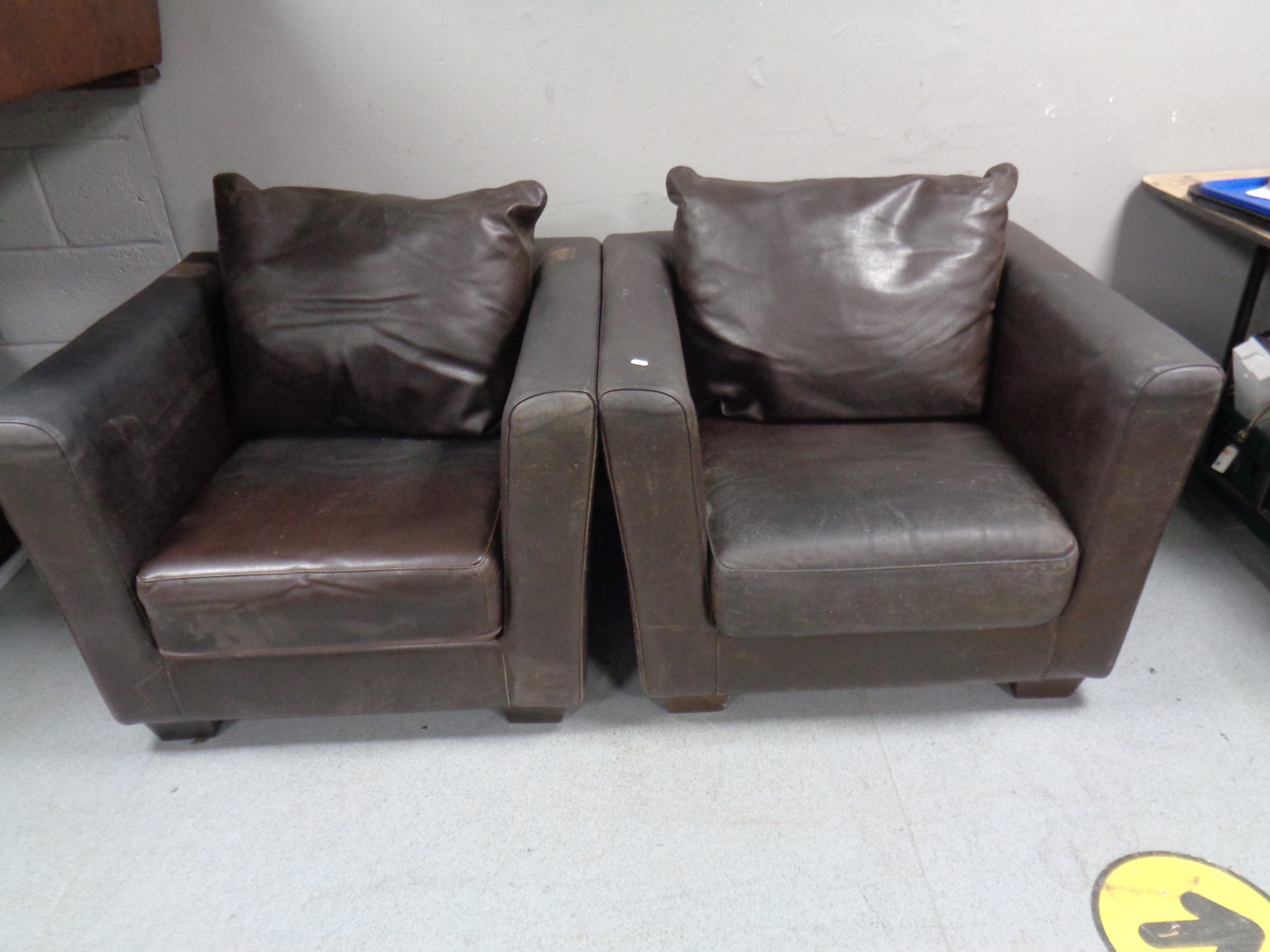 A pair of brown leather armchairs