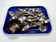 A tray containing two silver forks together with a quantity of plated cutlery together with a brass