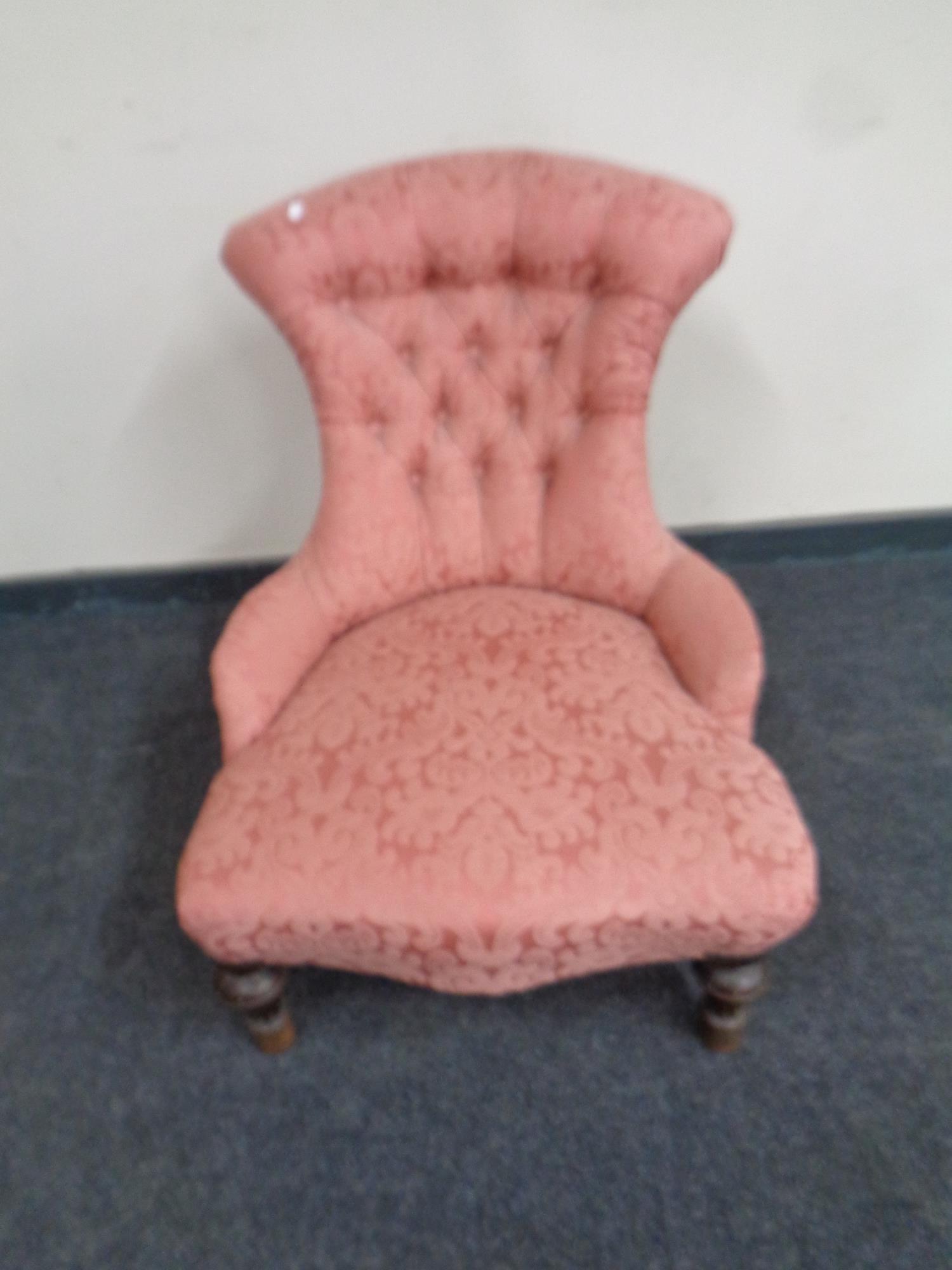 A Victorian nursing chair upholstered in a pink button back floral fabric