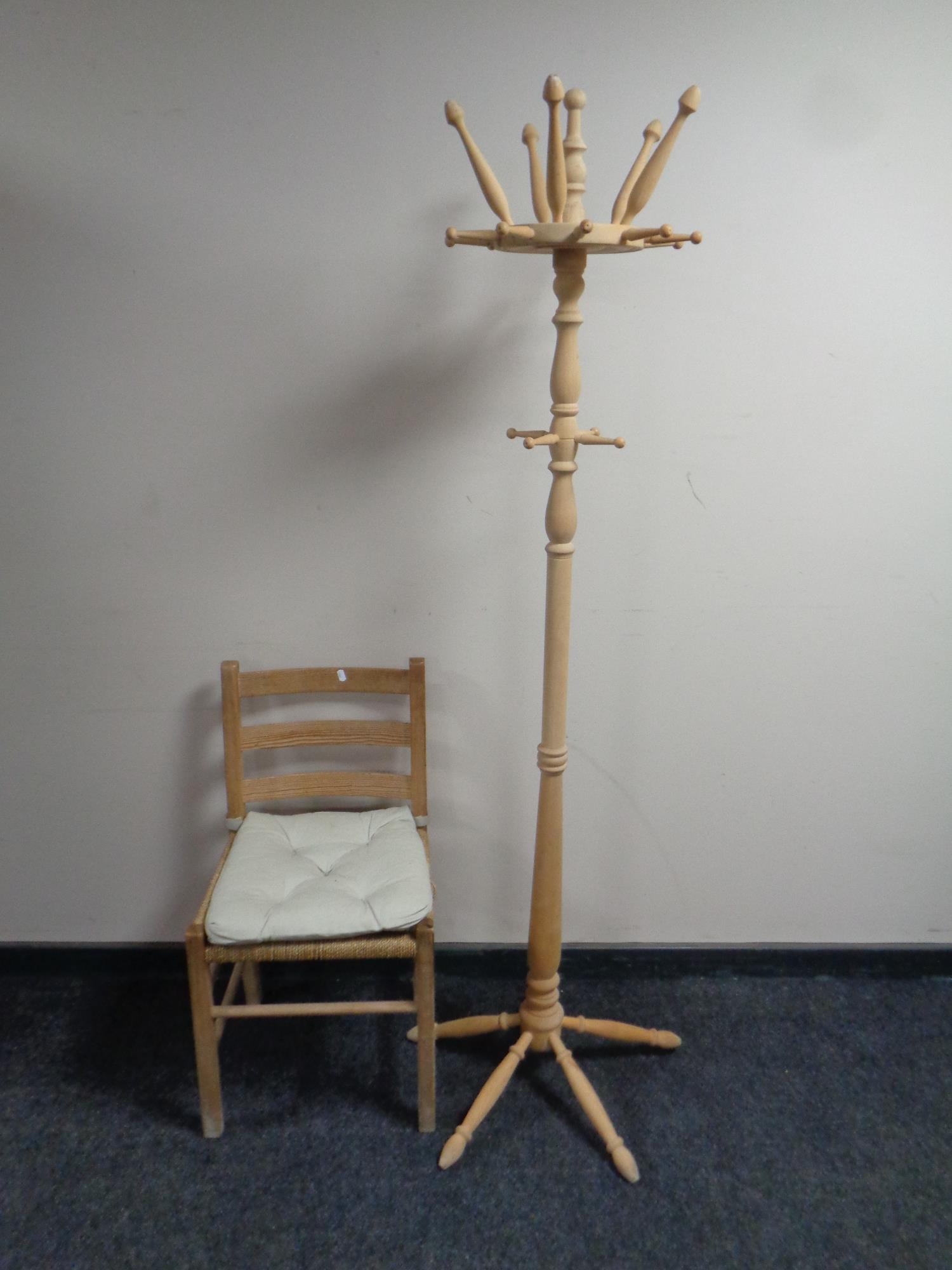 A stripped pine hat and coat stand together with a pine ladder back rush seated kitchen chair