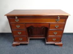 A Victorian style knee hole desk fitted seven drawers and slide on bracket feet