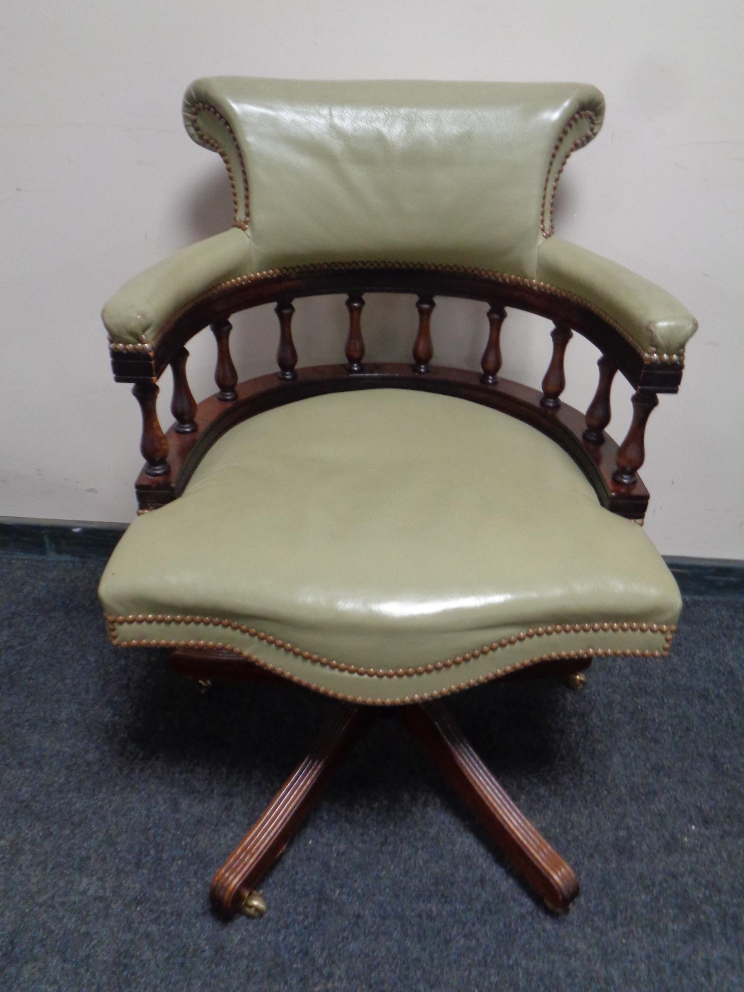 A captain's swivel desk chair upholstered in a light green leather