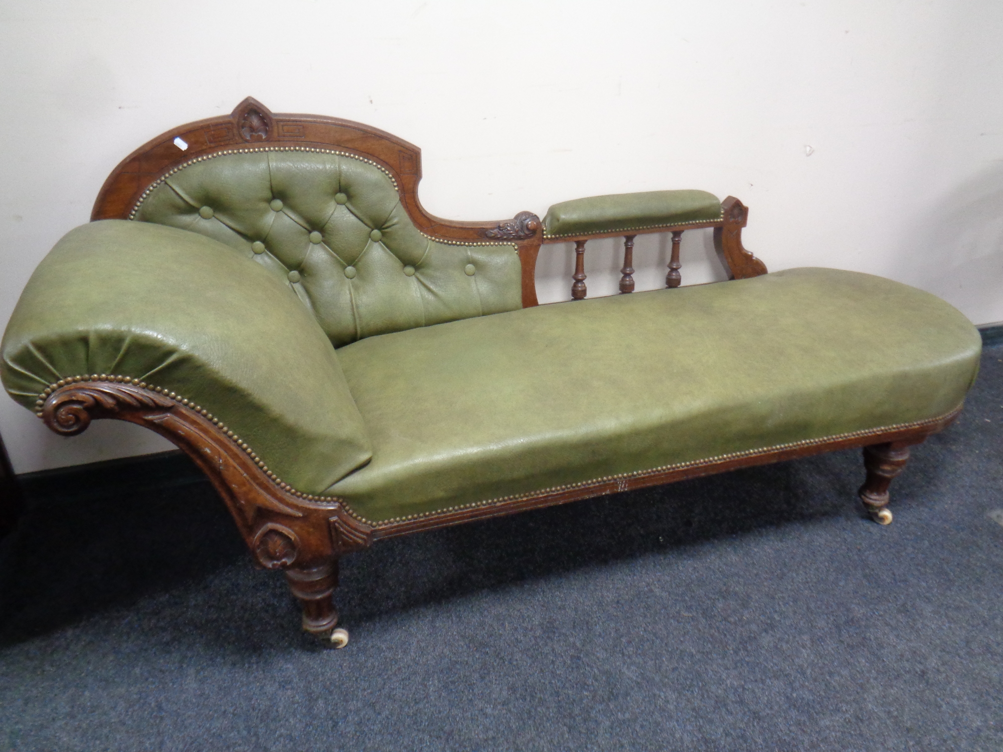 A late 19th century carved oak framed chaise longue upholstered in a green button leather