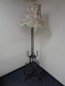 A wrought iron standard lamp with shade