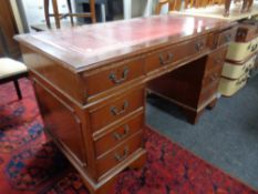 A reproduction mahogany twin pedestal writing desk fitted nine drawers with a red tooled leather