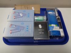 A tray containing Oral B toothbrush, Chanel perfume, Sanitize LED sanitizer,