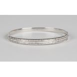 A white gold and diamond oval hinged bangle, the front mounted with a row of baguette cut diamonds