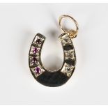 A gold, diamond and ruby pendant, designed as a horseshoe, mounted with three circular cut