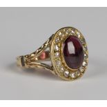 A gold, garnet and diamond oval cluster ring, collet set with an oval cabochon garnet within a