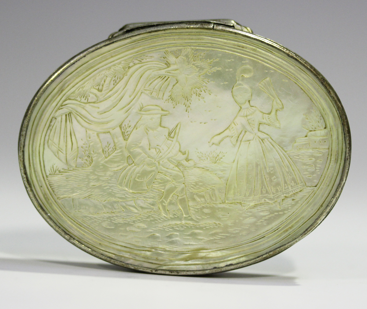 A mid to late 18th century silver mounted mother-of-pearl oval snuff box, the hinged lid carved in