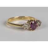 An 18ct gold, ruby and diamond ring, claw set with an oval cut ruby between two circular cut