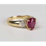 An 18ct gold, ruby and diamond ring, claw set with the pear shaped ruby in a raised design between