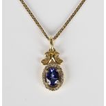A gold, tanzanite and diamond set oval pendant, claw set with the oval cut tanzanite within an