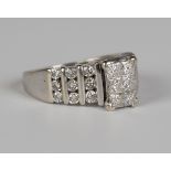 A white gold and diamond ring, mounted with six princess cut diamonds between diamond set stepped