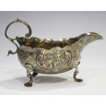 An early George III silver cream or sauceboat with foliate scroll handle, the body decorated in