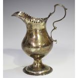 A George III silver cream jug of baluster form with scroll handle and beaded rim, on a circular