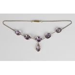 A gold and amethyst pendant necklace, the front claw set with a drop shaped amethyst pendant and