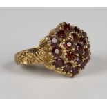 A 9ct gold and garnet hexagonal cluster ring, mounted with circular cut garnets between scroll