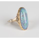 A gold and opal single stone ring, mounted with an oval opal between decorated shoulders,