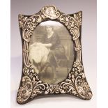 An Edwardian silver photograph frame of shaped rectangular form, embossed with flowers and foliate