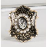 A Victorian mourning brooch, the centre set with an oval banded agate cameo, carved as a lily-of-