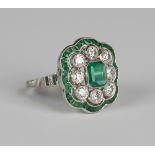 A platinum, emerald and diamond cluster ring of shaped rectangular form, mounted with a canted