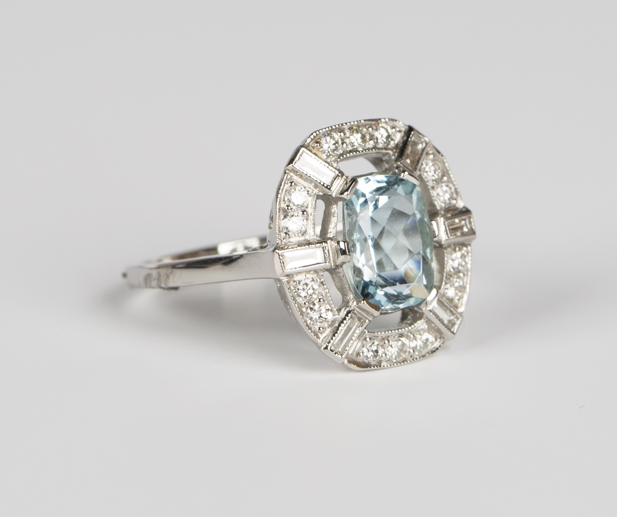 An aquamarine and diamond ring, claw set with an oval cut aquamarine within an openwork surround,
