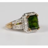 A 9ct gold ring, claw set with a rectangular step cut green gemstone within a surround of circular