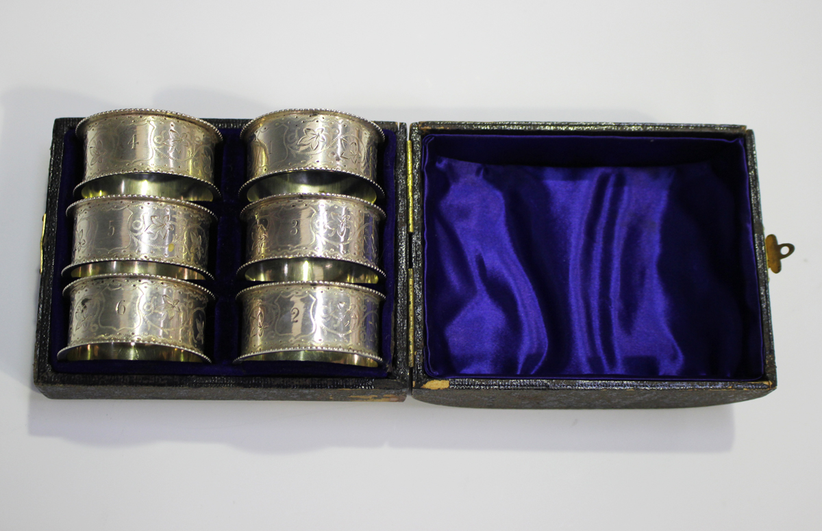 A set of six Victorian silver napkin rings with foliate engraved decoration between raised rims,