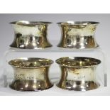 A set of four Edwardian silver napkin rings with beaded rims, Birmingham 1906 and 1907 by Broadway &
