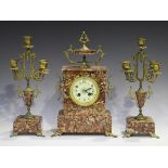 A late 19th century French gilt metal mounted rouge marble mantel clock garniture, the clock with