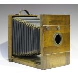 An early 20th century mahogany and brass field plate camera with black and blue tapering bellows,