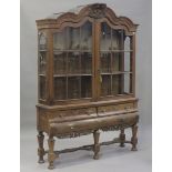 A 19th century Dutch oak display cabinet-on-stand, the shaped pediment with a leaf scroll