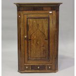 A George III provincial oak and mahogany banded hanging corner cupboard, the door inlaid with a