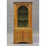 A 19th century pine corner cabinet, carved with foliate and stop fluted decoration, the arched