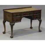 An early 20th century Queen Anne style mahogany kneehole writing table, carved with foliate