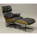 A modern black leather and walnut veneered plywood copy of an Eames lounge chair and matching