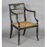 A Regency black and green painted elbow chair, heightened in gilt, the panel back painted with a