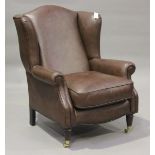 A modern brown leather wing back armchair by Laura Ashley, raised on fluted legs and brass