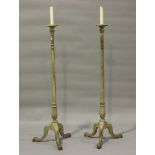 A pair of early 20th century limed oak lamp standards with fluted stems and carved tripod legs,
