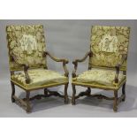 A pair of early 20th century French walnut framed elbow chairs, upholstered in floral woolwork,