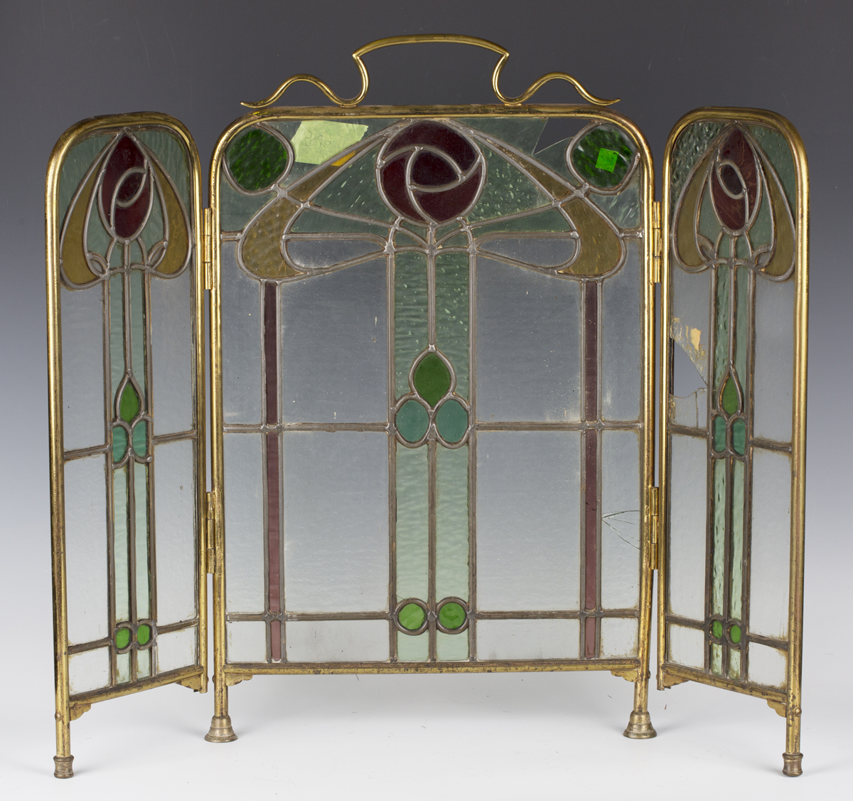 An early 20th century Arts and Crafts brass framed leaded and stained glass triptych firescreen,