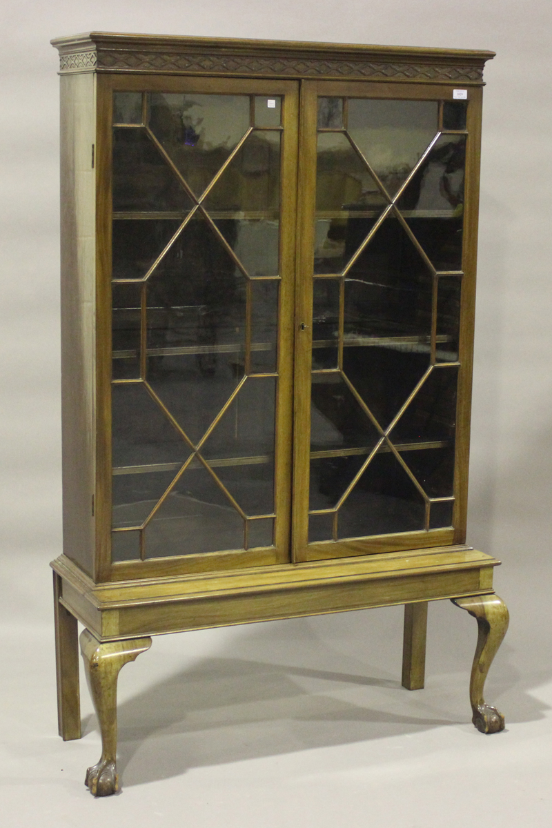 An Edwardian mahogany display cabinet-on-stand, enclosed by two astragal glazed doors, on cabriole