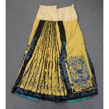 A Chinese yellow silk pleated apron skirt, late Qing dynasty, worked in coloured threads with panels
