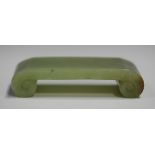 A Chinese jade brush rest, early 20th century, of scroll form, the stone of celadon green tone